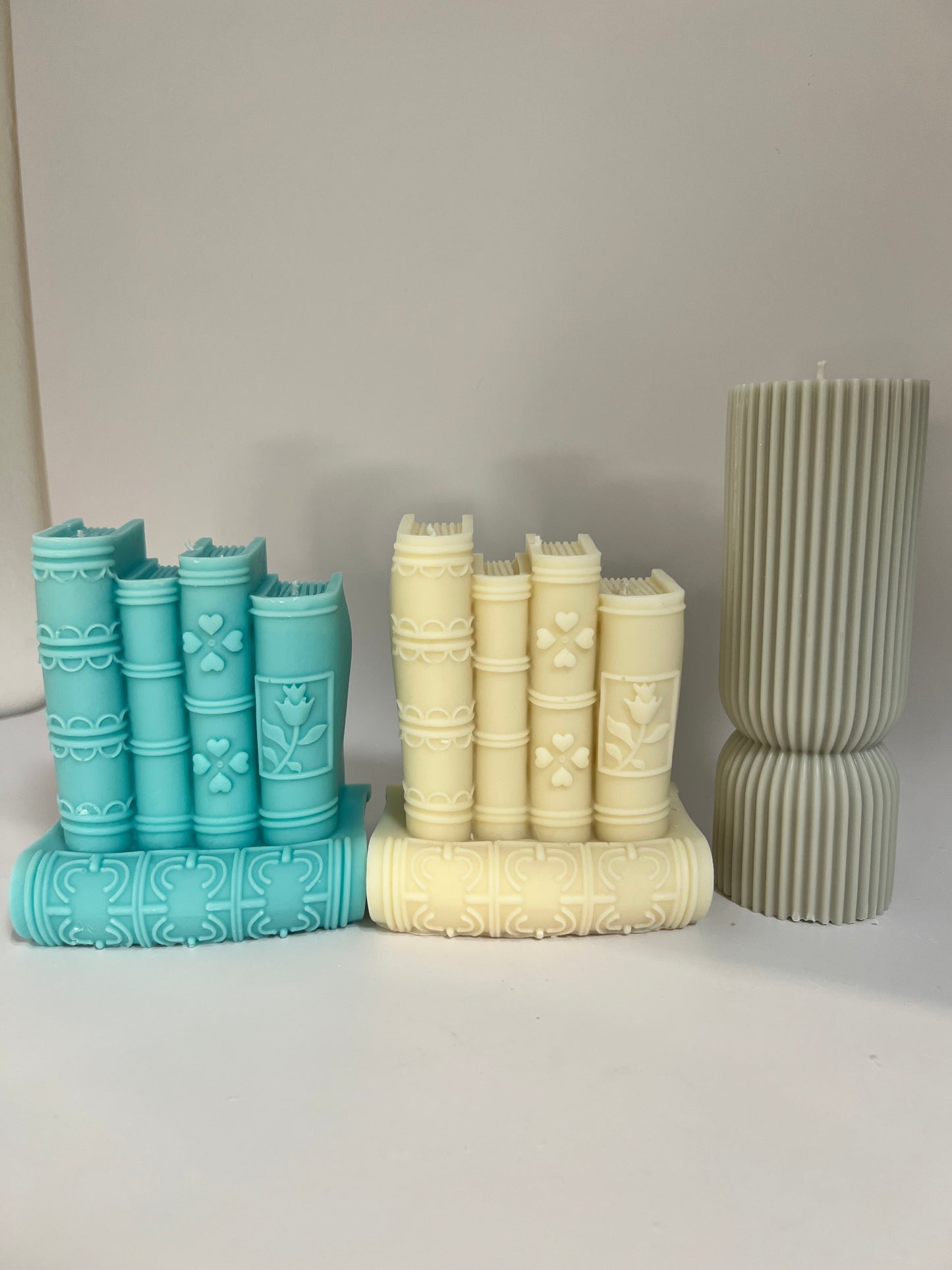“Luxury soy wax candle trio with two book-shaped candles in beige and blue inspired by Baccarat Rouge 540, and one gray pillar candle with Millionaire Man scent – handmade sculptural candles for home decor and gifting