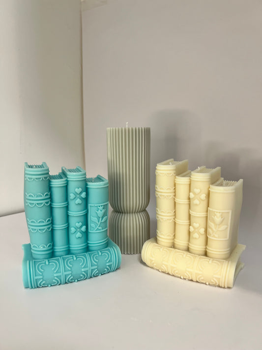 “Luxury soy wax candle trio with two book-shaped candles in beige and blue inspired by Baccarat Rouge 540, and one gray pillar candle with Millionaire Man scent – handmade sculptural candles for home decor and gifting