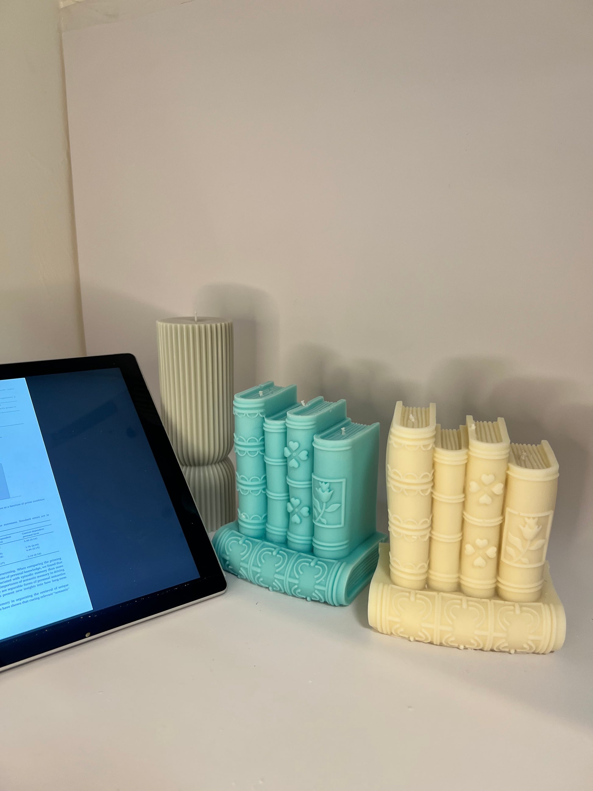 “Luxury soy wax candle trio with two book-shaped candles in beige and blue inspired by Baccarat Rouge 540, and one gray pillar candle with Millionaire Man scent – handmade sculptural candles for home decor and gifting