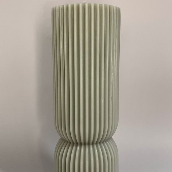 Scented pillar candle in soft pastel tones, featuring Millionaire Man inspired aroma for upscale ambiance